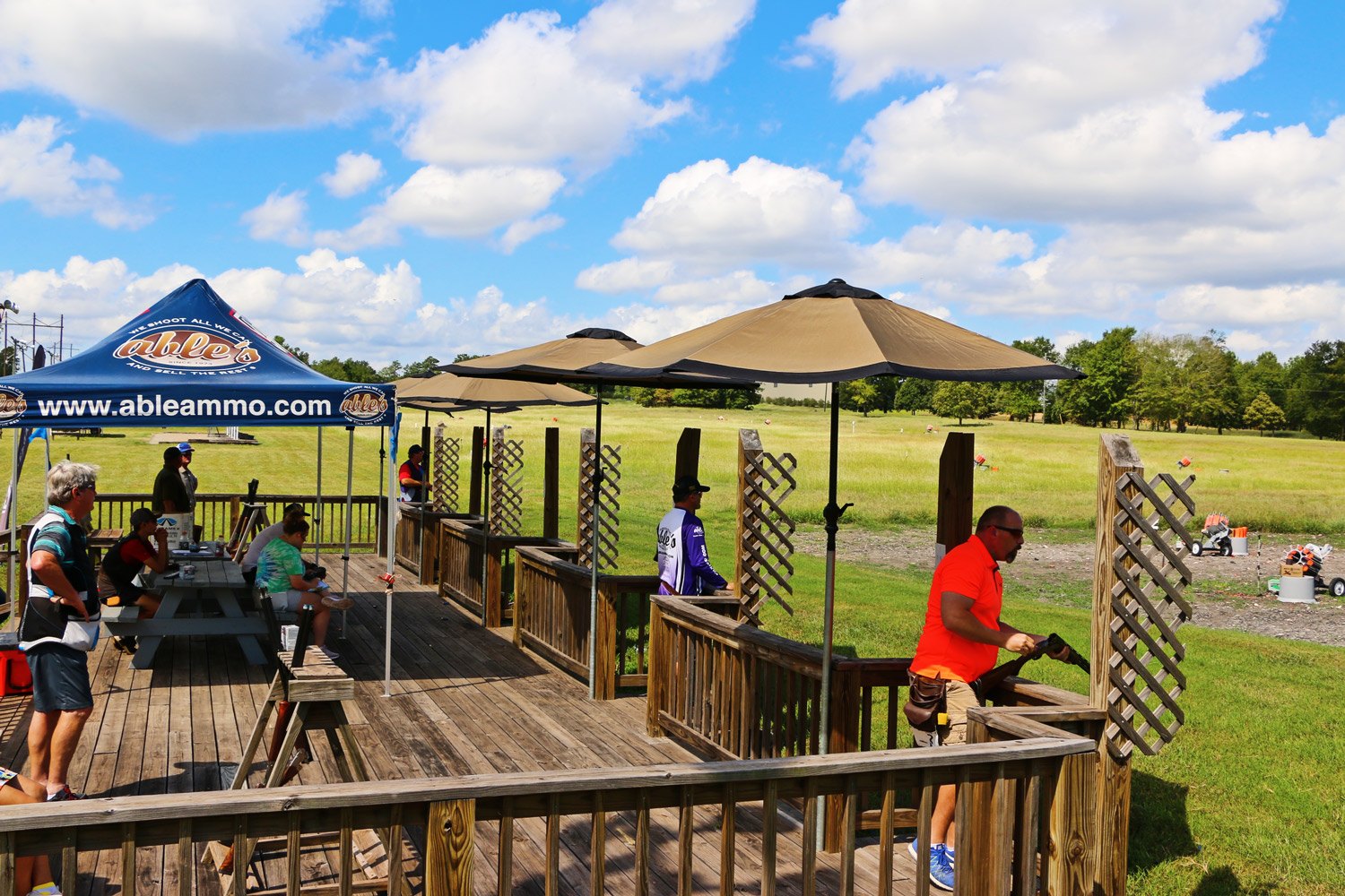 Shooters on the wooden 5-stand deck under shade umbrellas